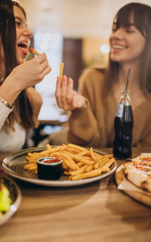 Two girls friends eating pizza cafe